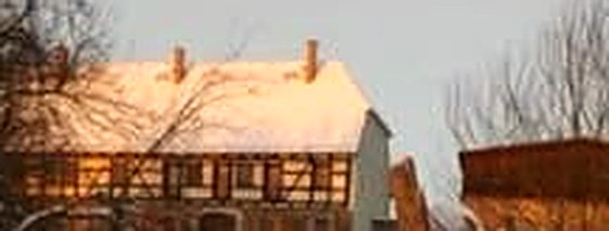 Der Vierseithof im Winter — Fachwerk unter Schnee im warmen Abendlicht